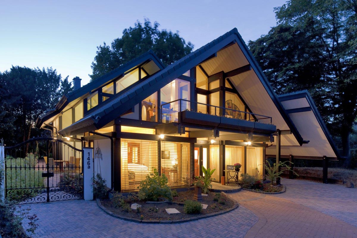 Modern Marin County hillside home with an elevated residential parking deck, parked cars, structural supports, retaining walls, and a curved driveway access ramp.